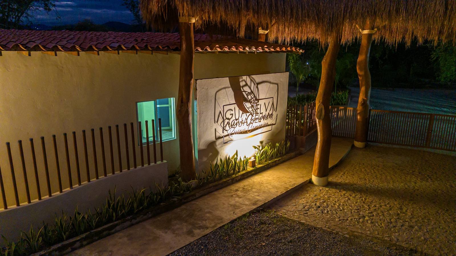 Muro iluminado con el logo de Agua Selva al anochecer